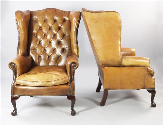 A pair of brown leather wingback armchairs,